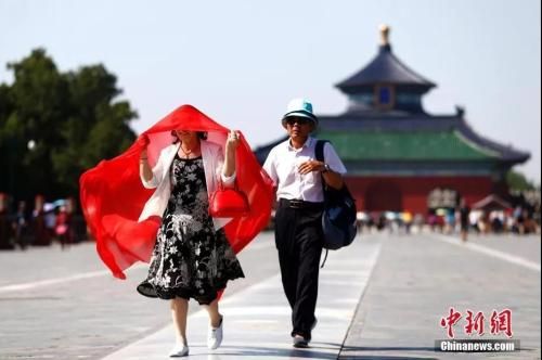 资料图：5月23日，一名游客用纱巾遮阳。中新社记者 富田 摄