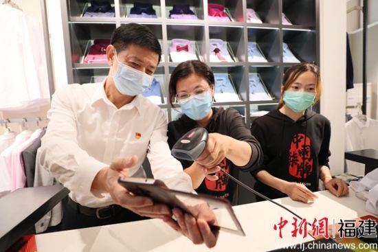 泉州市委常委、晋江市委书记刘文儒(左一)购物后进行扫码支付。
