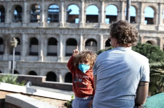 4月27日，一名父亲带着孩子在意大利首都罗马的斗兽场附近晒太阳。新华社发