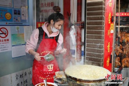 上海宝山区一个农贸市场里，一家煎饼铺店主一边做煎饼，一边上网直播并与网友交流。 殷立勤 摄