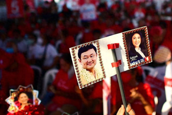 一名為泰黨的支持者舉著一張標語牌，上面有泰國前總理他信和英拉的照片。（資料圖）圖片來源：視覺中國