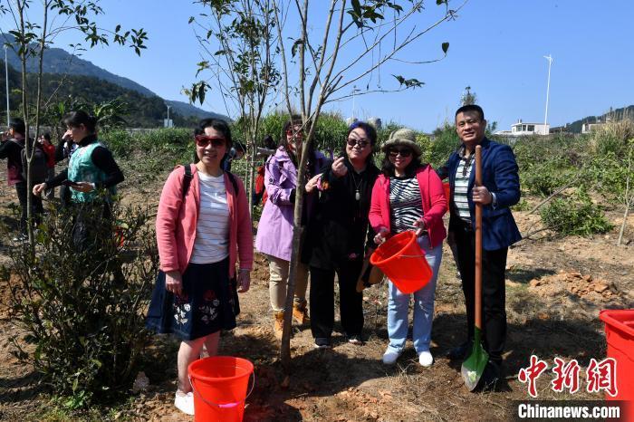图为参加植树活动的两岸各界妇女代表及嘉宾在自己种的小树前合影留念。　吕明 摄